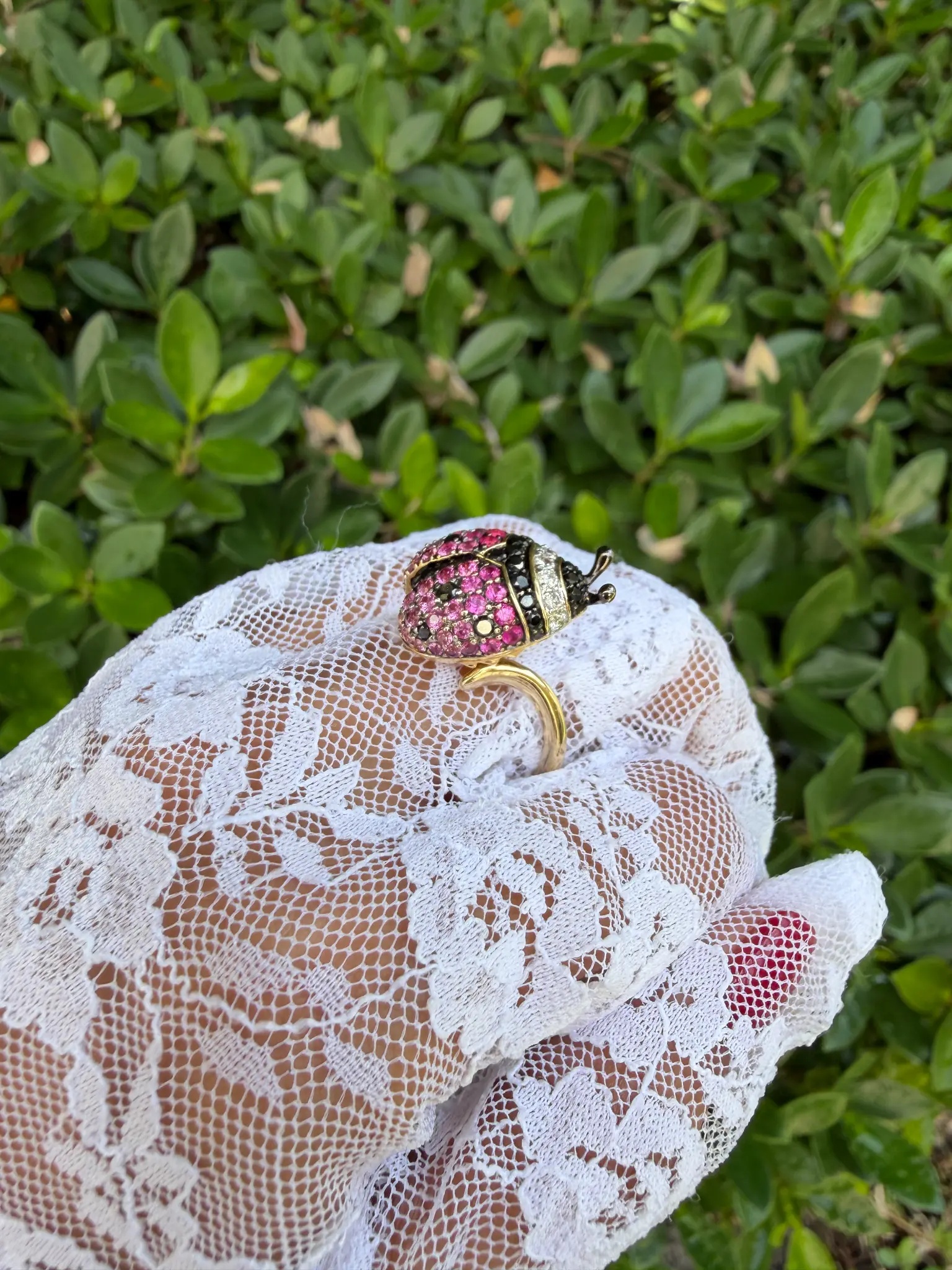 Estate ladybug ring on lace-gloved hand outdoors